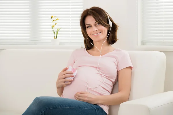 Femme enceinte avec écouteurs — Photo