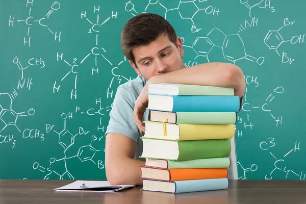 Homme appuyé sur une pile de livres — Photo