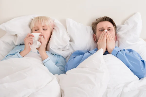 Paar pustet sich im Bett die Nase aus — Stockfoto
