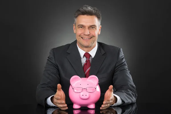 Affärsman som sitter med Piggybank — Stockfoto