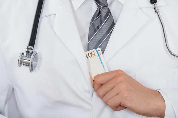 Médico poniendo dinero en el bolsillo — Foto de Stock