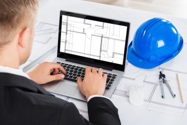 Architect Analyzing Blue Print On Computer clipart