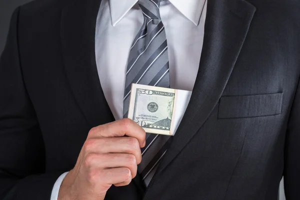 Бизнесмен кладет взятку в карман костюма — стоковое фото