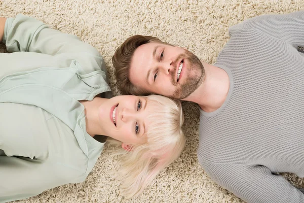 Casal feliz deitado no tapete — Fotografia de Stock