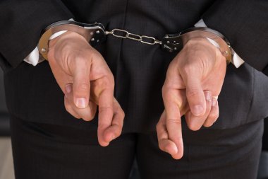 Kelepçe ve parmak çarpı işareti ile işadamı