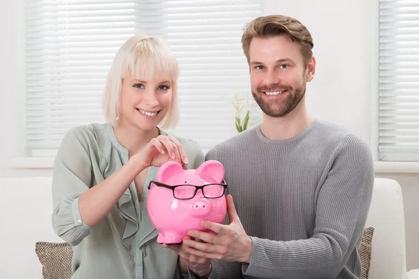 Casal de inserção de moeda no Piggybank — Fotografia de Stock