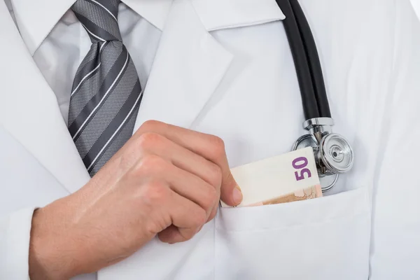 Lekarz oddanie pieniędzy w kieszeni — Stockfoto
