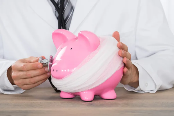 Arts houden stethoscoop piggy bank — Stockfoto
