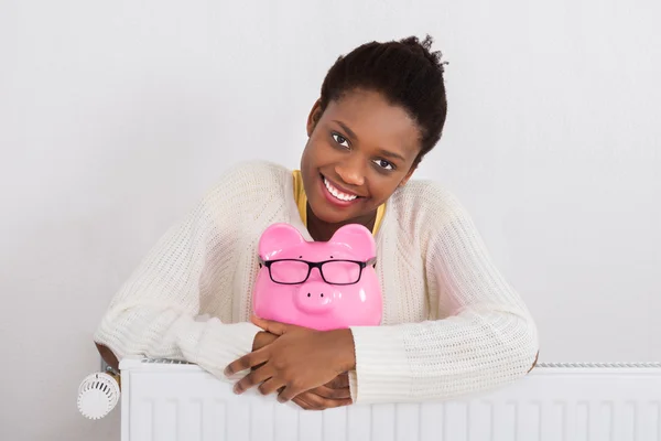 Woman With Piggybank Leaning On Radiator — Stock Photo, Image