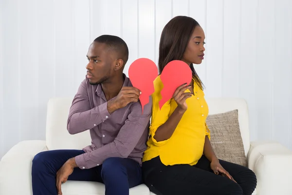 Triste casal segurando coração quebrado — Fotografia de Stock