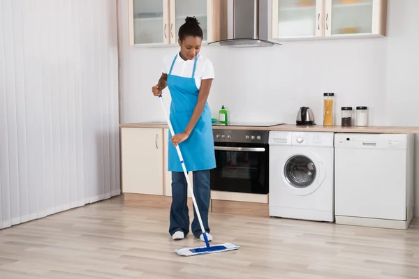 Mulher zeladora esfregando chão na cozinha — Fotografia de Stock