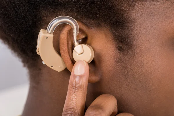 Mulher vestindo aparelho auditivo na orelha — Fotografia de Stock