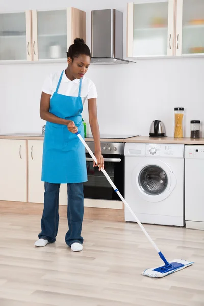 Mulher zeladora esfregando chão na cozinha — Fotografia de Stock