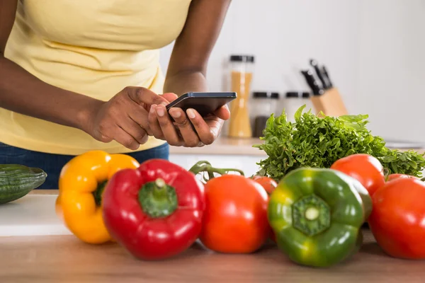 Frau benutzt Handy in Küche — Stockfoto