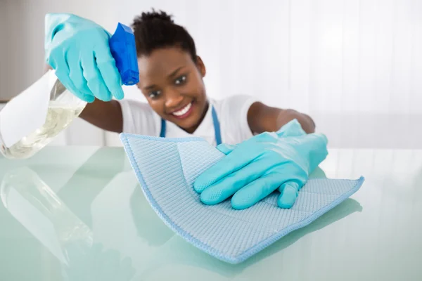 Feliz feminino zelador mesa de limpeza — Fotografia de Stock