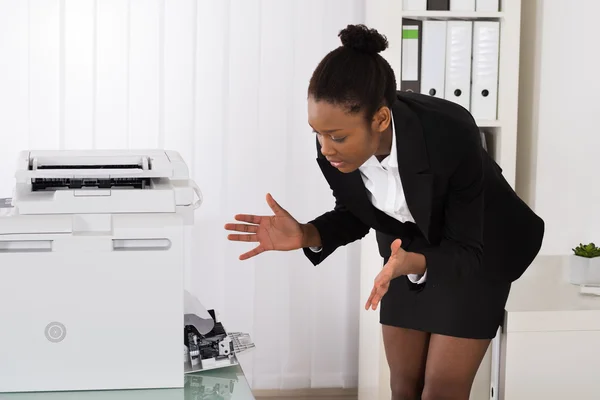 Geschäftsfrau schaut auf Papier, das im Drucker steckt — Stockfoto