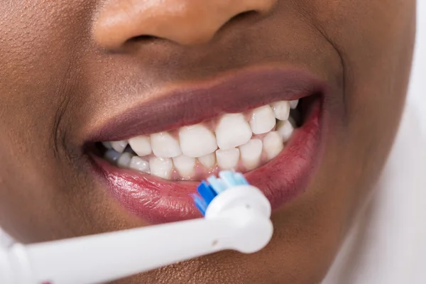 Mulher escovando dentes com escova de dentes elétrica — Fotografia de Stock