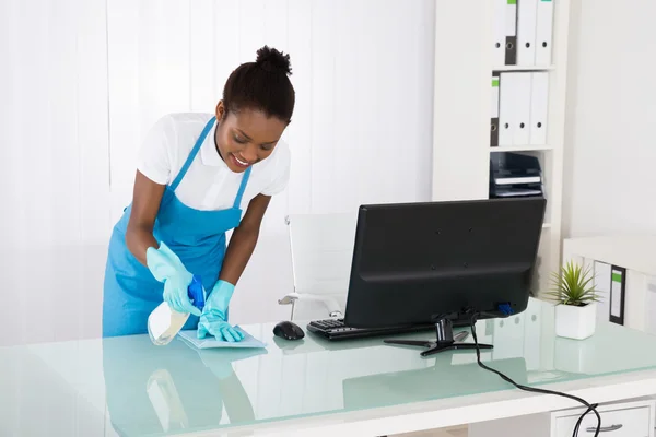 Vrouwelijke Janitor schoonmaak Bureau met doek — Stockfoto