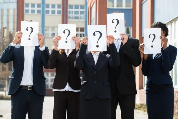Empresarios escondiendo caras detrás de signo de interrogación — Foto de Stock