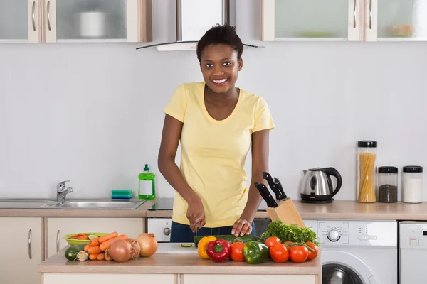 Mulher feliz cortando legumes — Fotografia de Stock