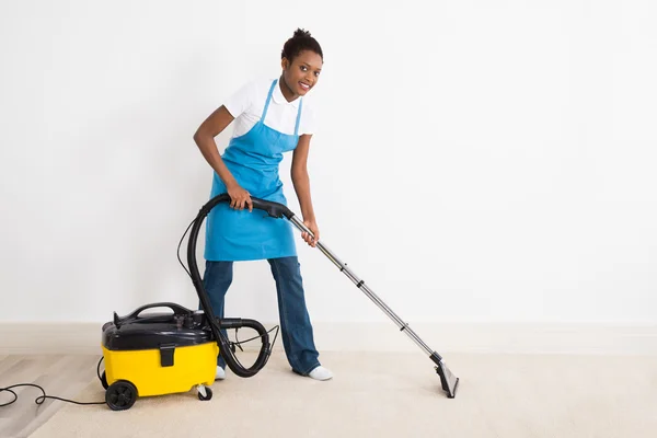 Janitor feminino usando aspirador de pó — Fotografia de Stock