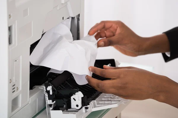 Geschäftsfrau entfernt Papier, das im Drucker steckt — Stockfoto