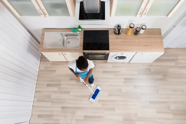 Conserje hembra limpieza piso en cocina — Foto de Stock