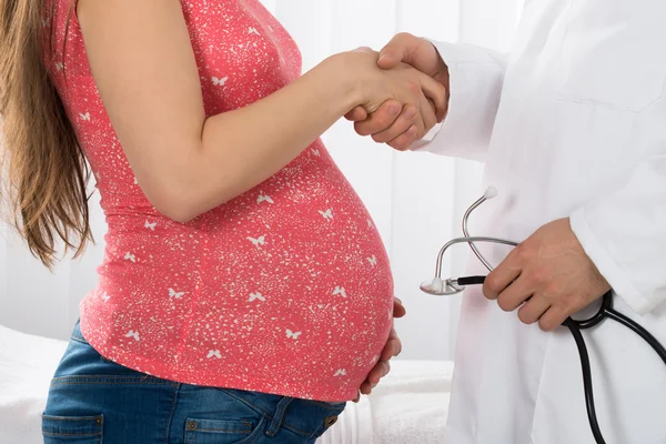 Femme enceinte serrant la main du médecin — Photo