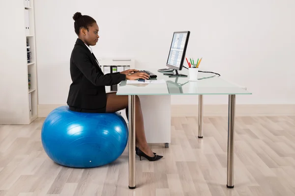 Mujer de negocios sentada en la pelota de fitness en la oficina —  Fotos de Stock