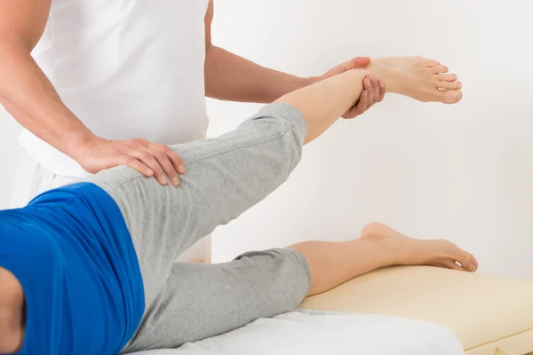 Terapeuta dando massagem na perna para a mulher — Fotografia de Stock