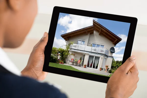 Person schaut Haus auf digitalem Tablet an — Stockfoto