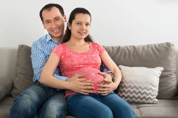 W ciąży para siedzi na kanapie — Zdjęcie stockowe