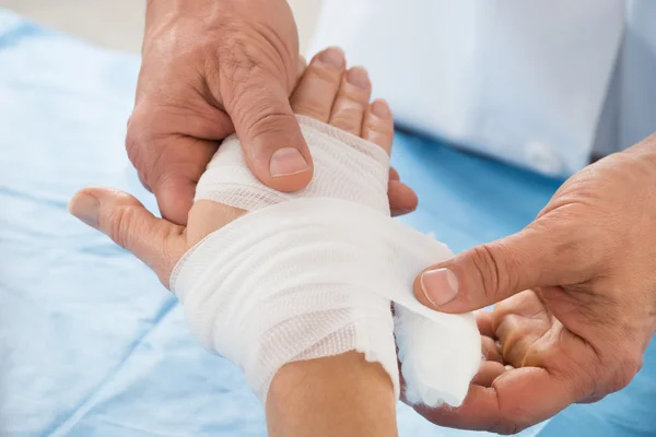 Person wickelt Verband zu Patient — Stockfoto