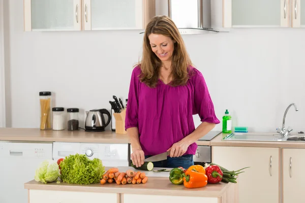 Mujer cortando verduras en la cocina — Foto de Stock