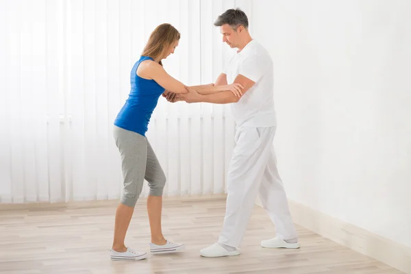 Fisioterapeuta asistiendo a la mujer para hacer ejercicio —  Fotos de Stock