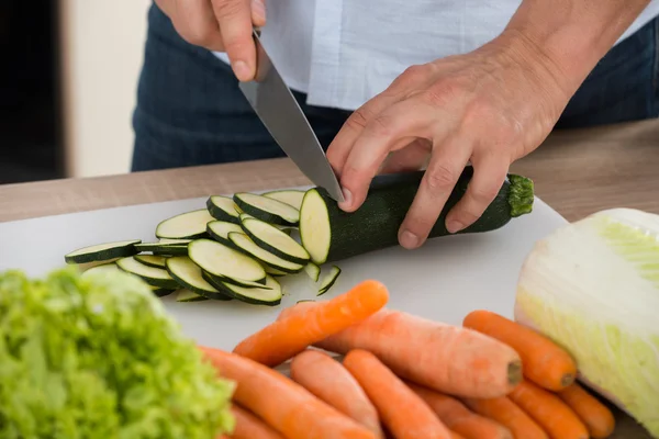 Homme coupe légumes dans la cuisine — Photo