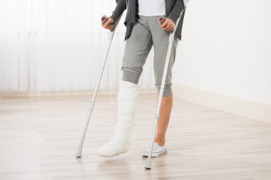 Woman Using Crutches While Walking clipart
