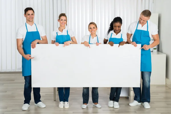 Limpiadores sosteniendo banner en la oficina — Foto de Stock