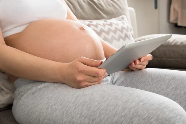 Femme enceinte utilisant une tablette numérique — Photo