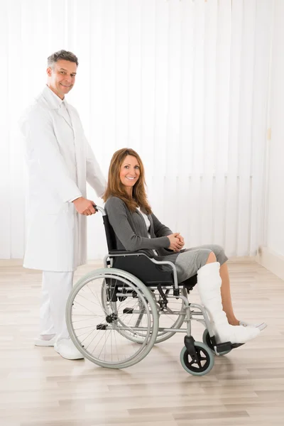Médico asistiendo a la mujer en silla de ruedas — Foto de Stock