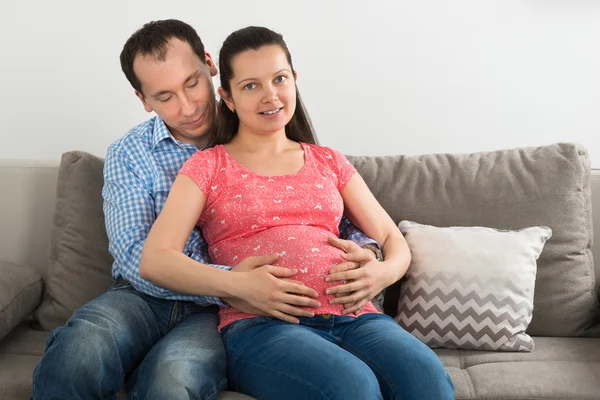 W ciąży para siedzi na kanapie — Zdjęcie stockowe