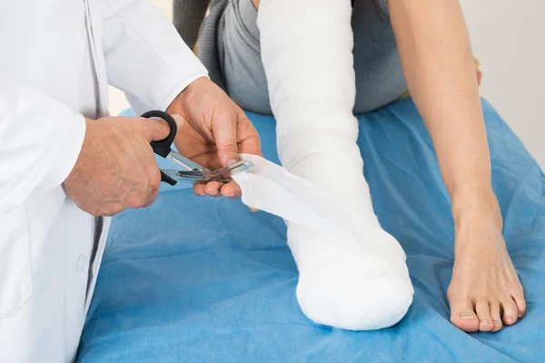Lekarz bandażowanie nogi pacjenta — Zdjęcie stockowe