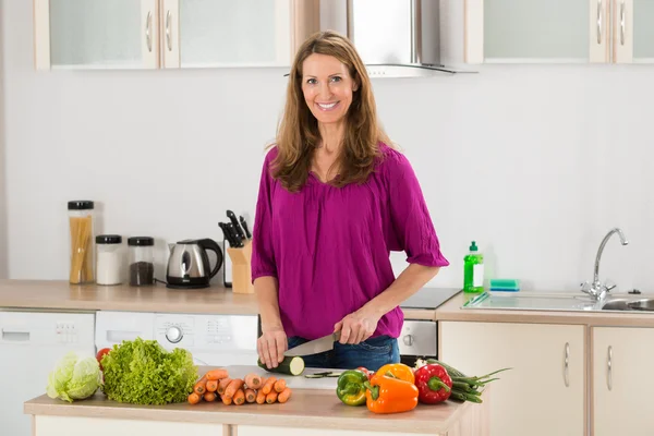 Femme coupe des légumes dans la cuisine — Photo