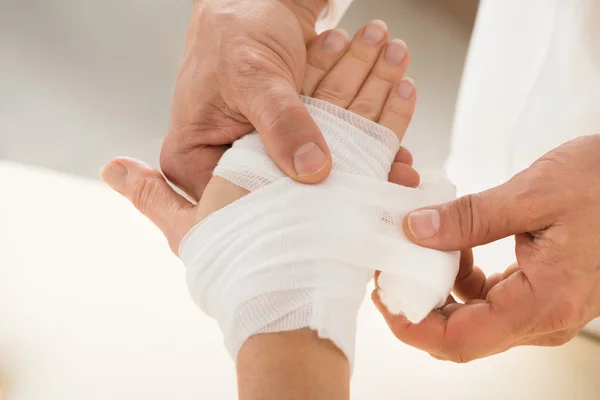 Person wickelt Verband zu Patient — Stockfoto