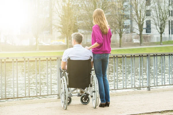 Mujer con su marido discapacitado en silla de ruedas —  Fotos de Stock