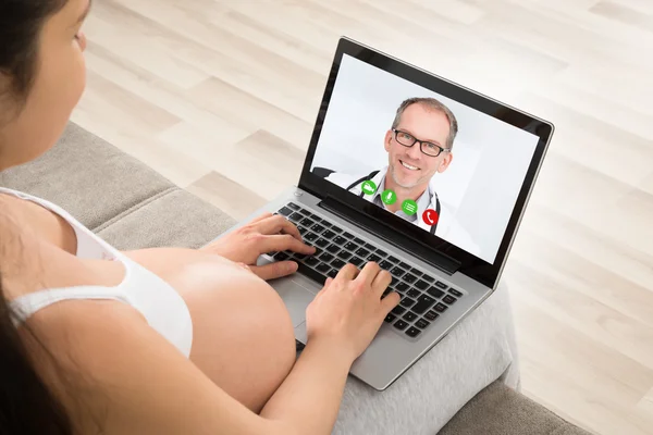 Schwangere telefoniert mit Arzt am Laptop — Stockfoto