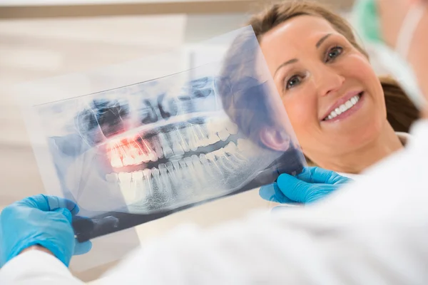 Dentista com raio-X de dentes na frente da mulher — Fotografia de Stock