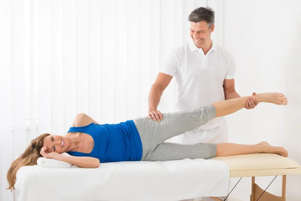 Terapeuta masculino dando massagem na perna para a mulher — Fotografia de Stock