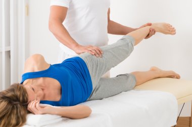 Male Therapist Giving Leg Massage To Woman clipart