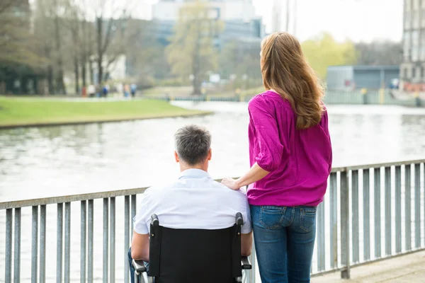 Женщина со своим мужем-инвалидом на инвалидной коляске — стоковое фото